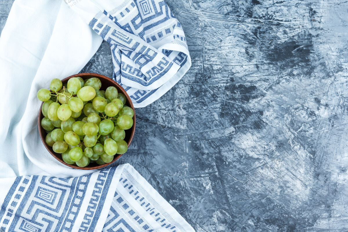 美味绿色的葡萄放在一个粘土碗里 背景是脏兮兮的灰泥和厨房毛巾有机健康串