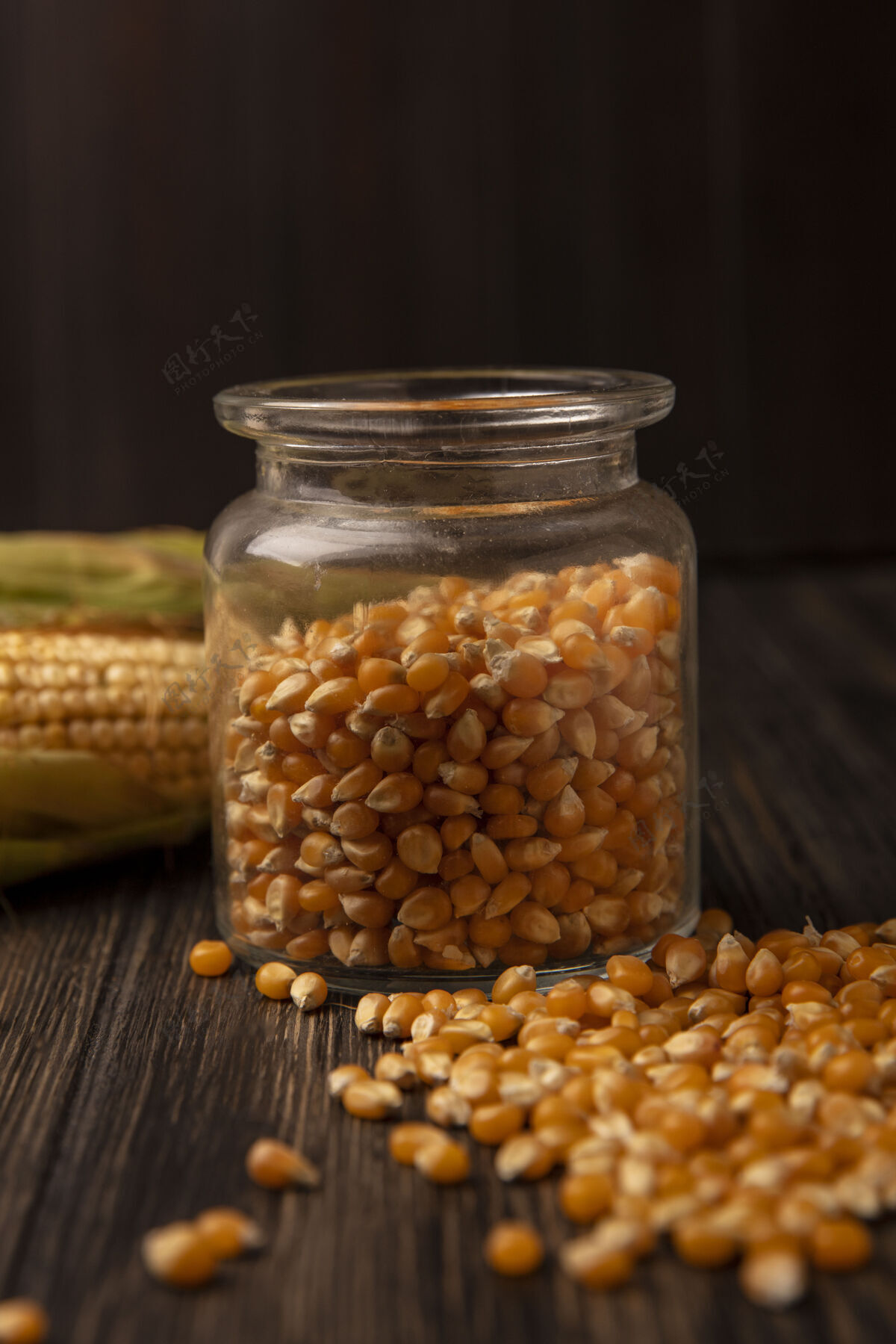 果仁侧视图新鲜玉米粒上的玻璃罐与新鲜玉米和玉米粒隔离在一个木墙上景观有机玉米