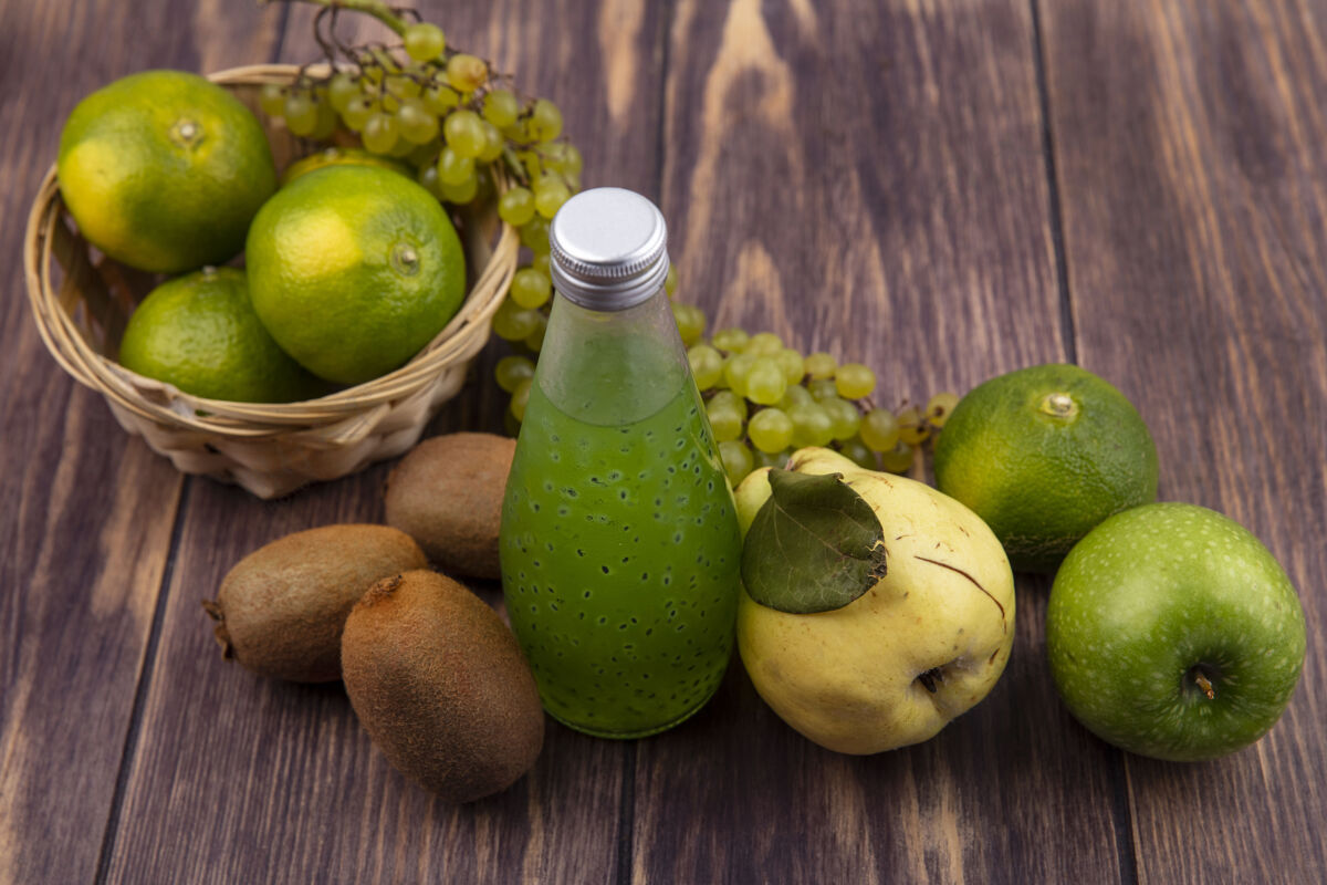 梨侧视图果汁瓶与梨 猕猴桃 橘子 苹果和葡萄在一个篮子里的木制墙壁果汁葡萄苹果