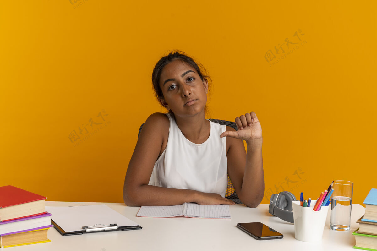 橙色坐在书桌旁拿着学习工具的自信的年轻女学生指着自己女人点她自己