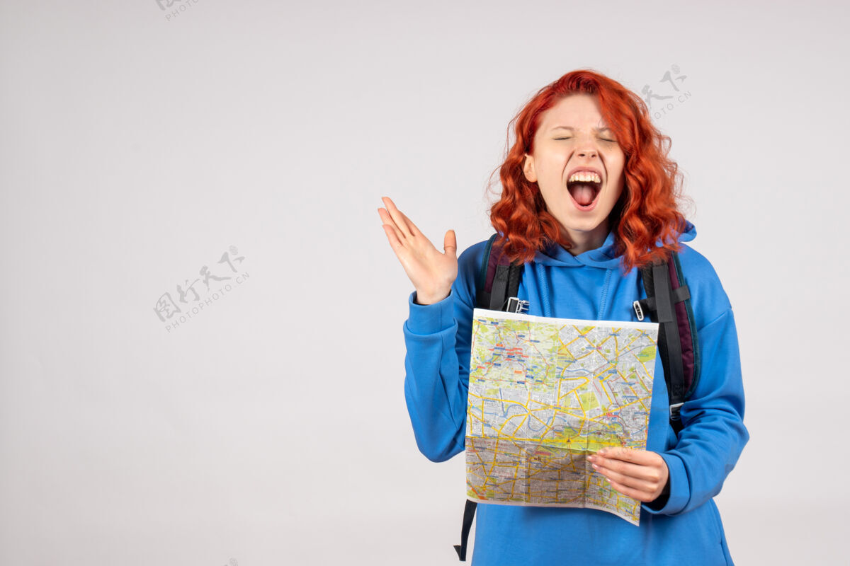 旅行年轻女性的正面图 白色墙上有背包和地图漂亮前面人