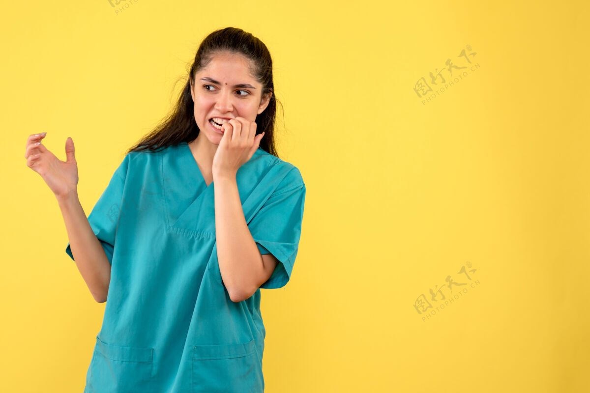 成人穿着制服的女医生把手放在黄色墙壁上的嘴上的正视图肖像快乐人