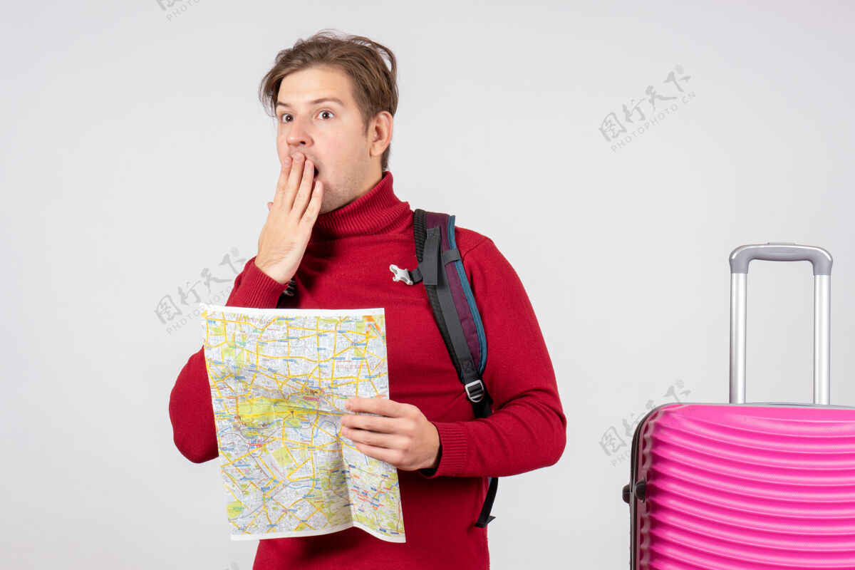 地图男游客的正面图 白色墙上有背包和地图快乐漂亮前面