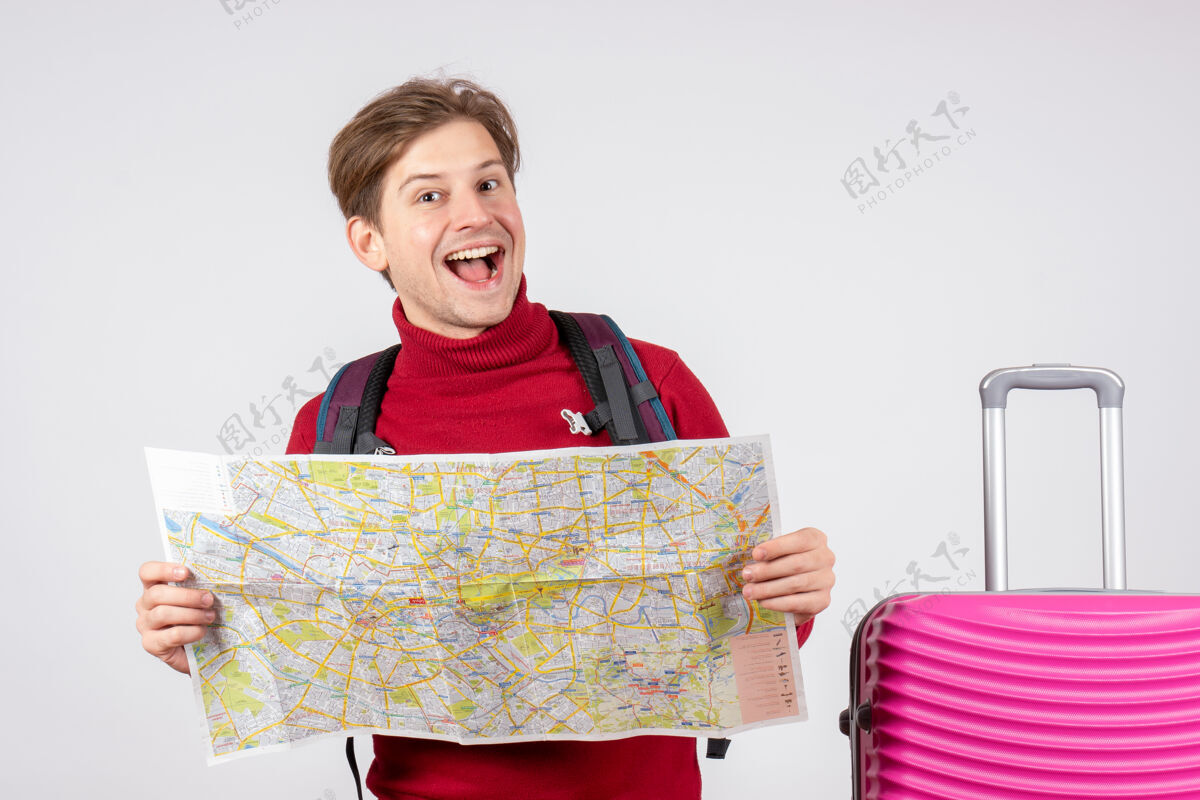 快乐男游客的正面图 白色墙上有背包和地图包人背包