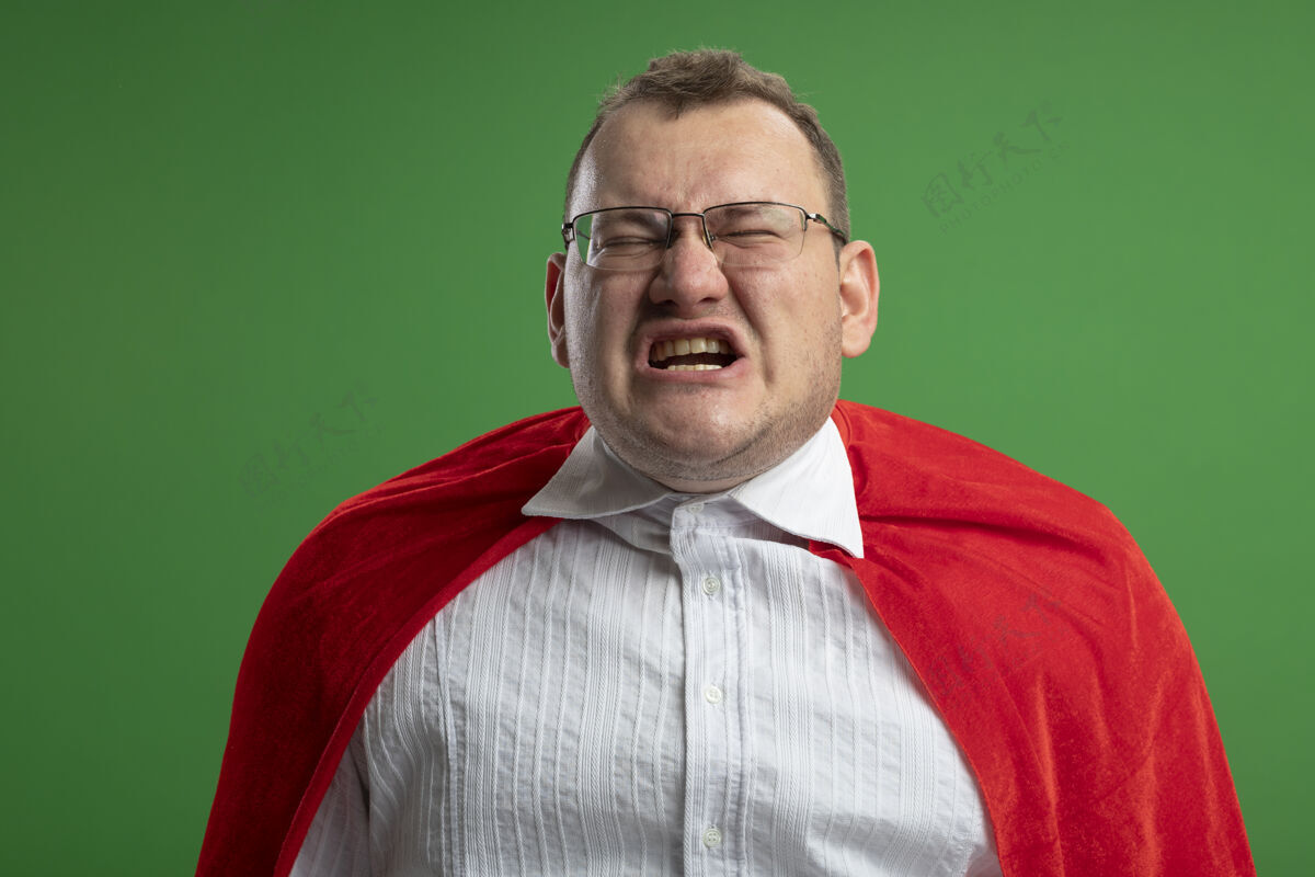 超级英雄恼怒的成年斯拉夫超级英雄穿红斗篷戴着眼镜闭着眼睛隔离在绿墙上穿斯拉夫人封闭