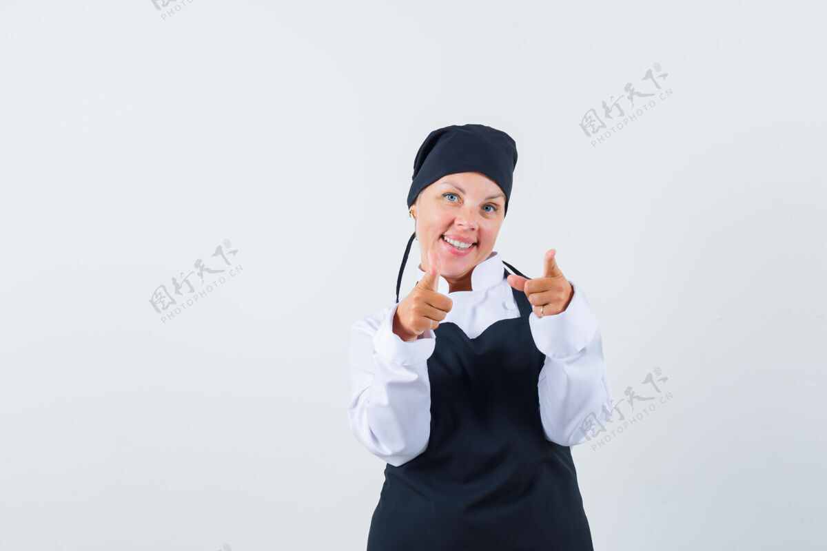 黑发女厨师穿着制服 围着围裙指着摄像机 看上去很开心 正对着镜头亚洲人化妆快乐