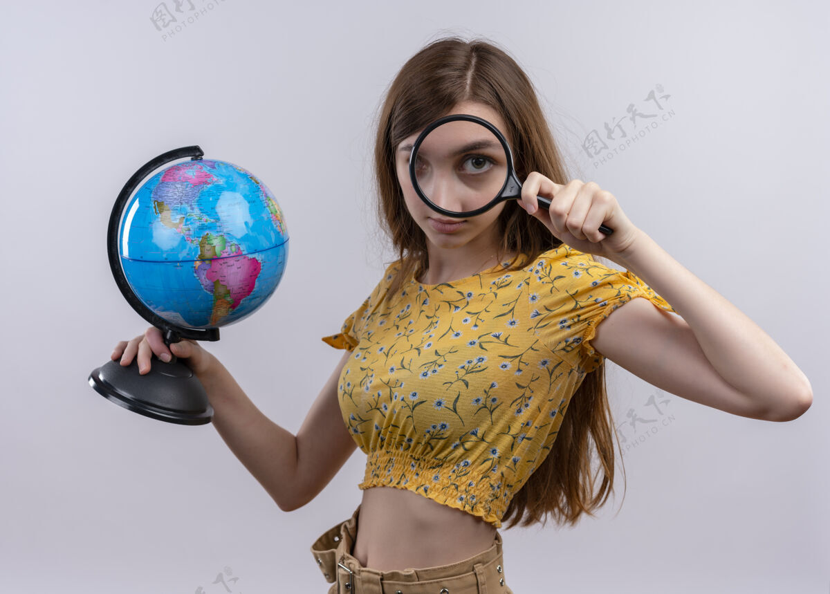 地球仪年轻女孩拿着地球仪 透过放大镜在隔离的白墙上看玻璃年轻人拿着