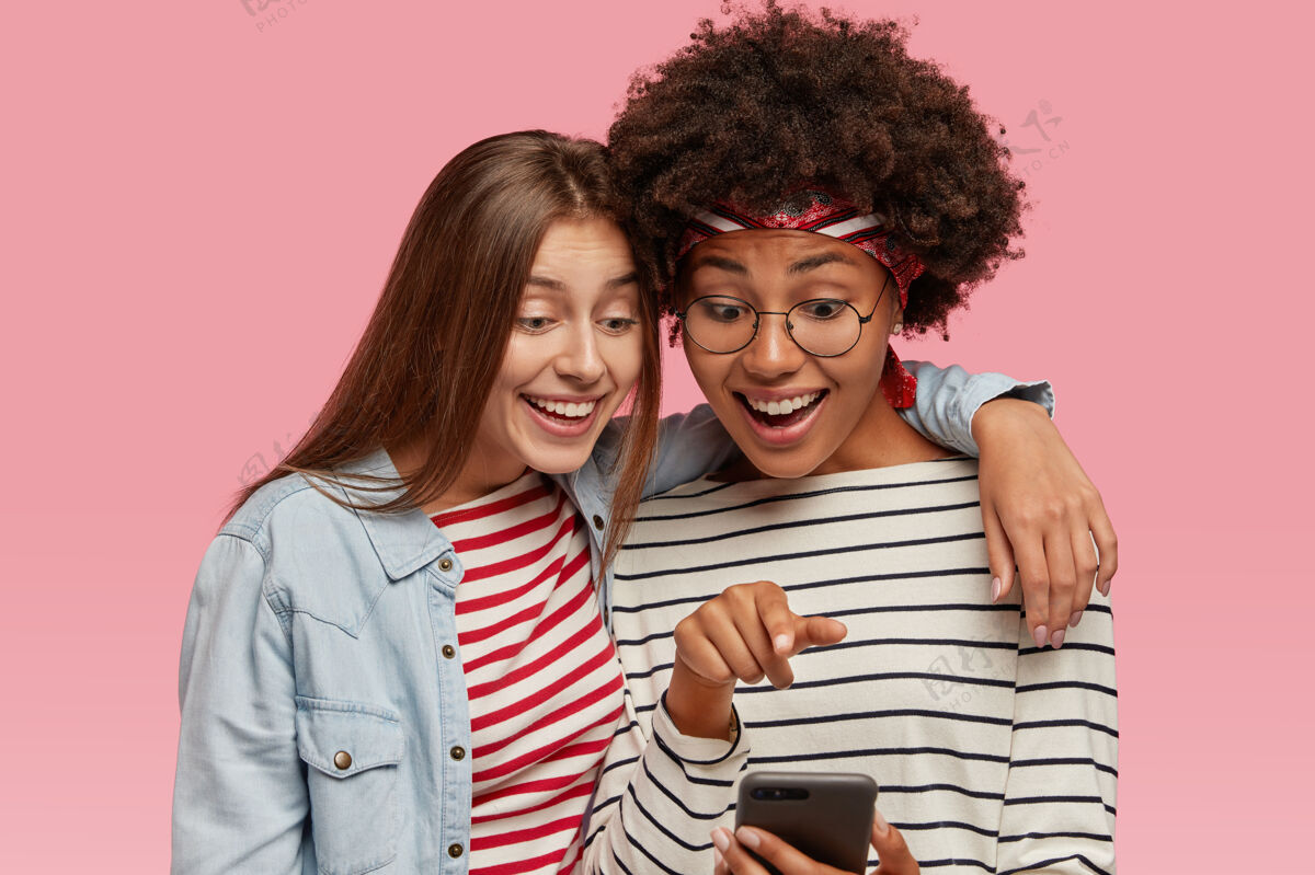 手机友好的女性朋友在一起玩得很开心 拥抱并在手机上观看有趣的视频友谊手机友谊