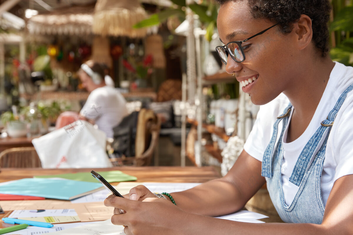 无线快乐的黑人金融家在自助餐厅做文书工作的侧面镜头咖啡休闲文件