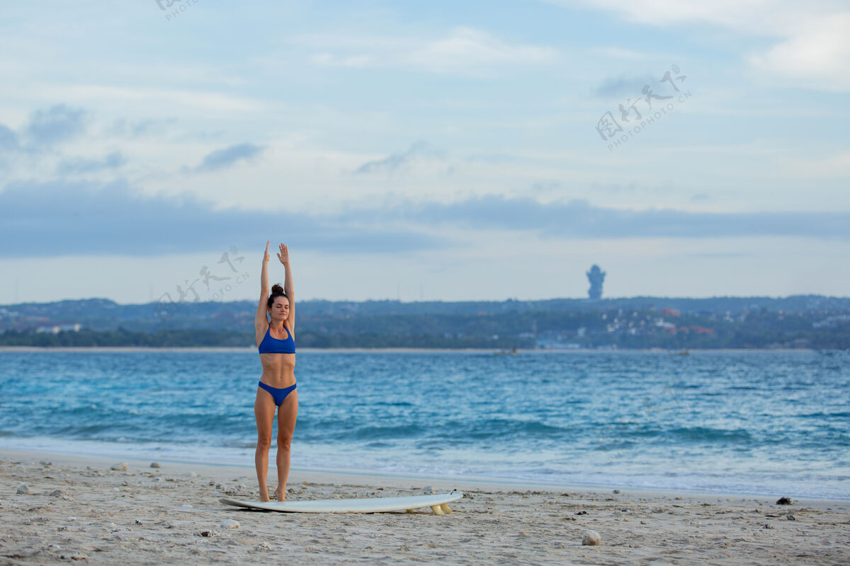 沙滩美丽的女孩伸展在沙滩上冲浪板冲浪成人沙滩