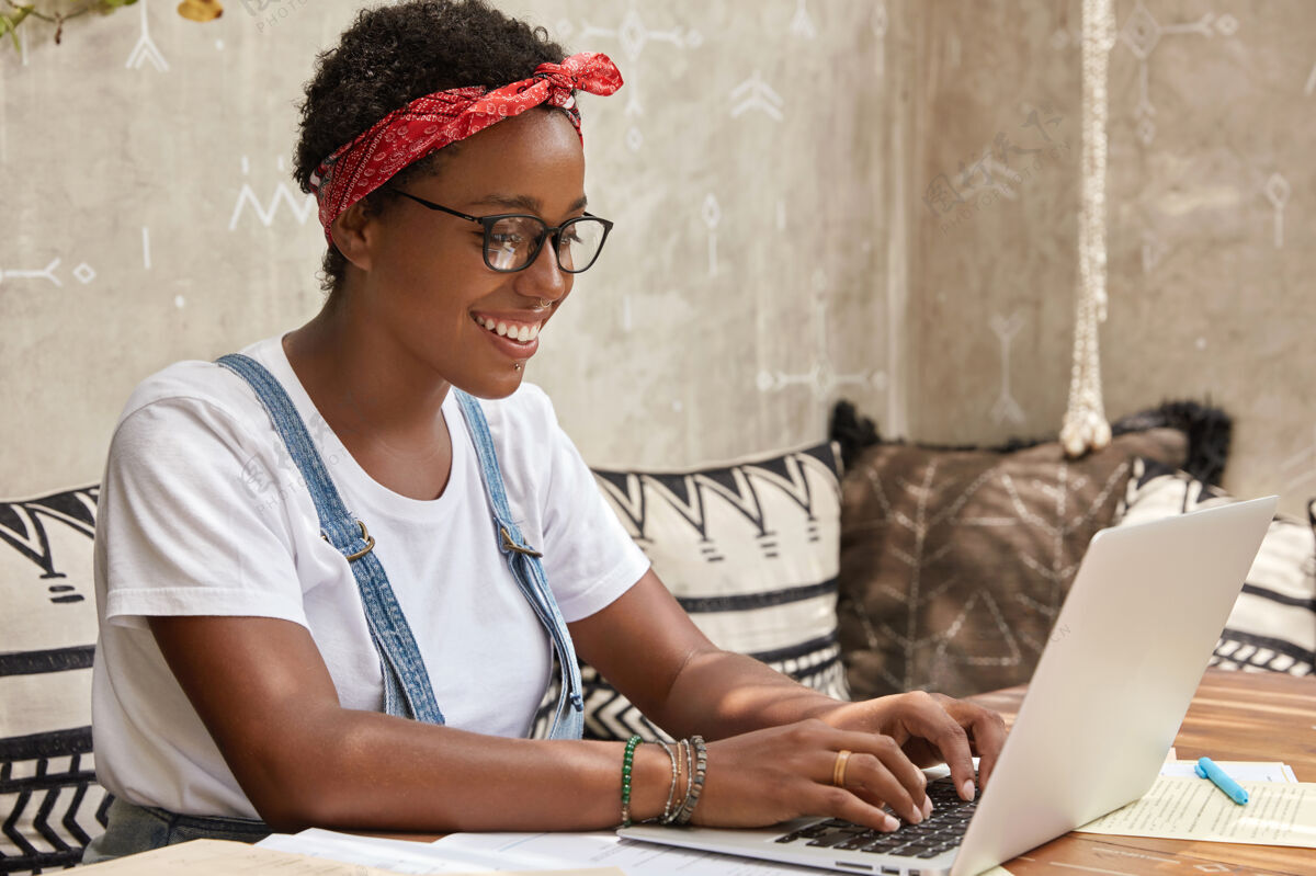 公共积极的年轻女士自由职业者在眼镜键盘上的笔记本电脑信息满意头带博主