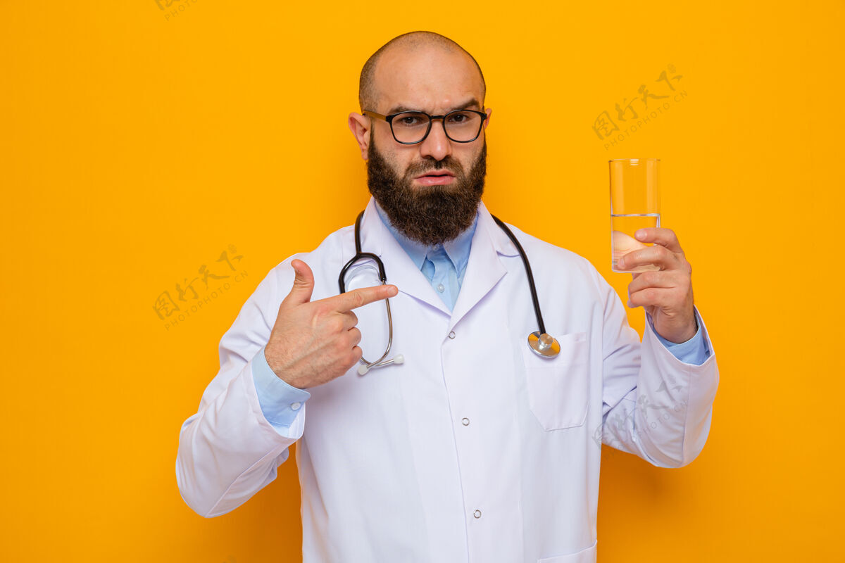 手指大胡子男医生 身穿白大褂 脖子上戴着听诊器 戴着眼镜 手里拿着一杯水 用食指指着 表情严肃严重的男人拿着