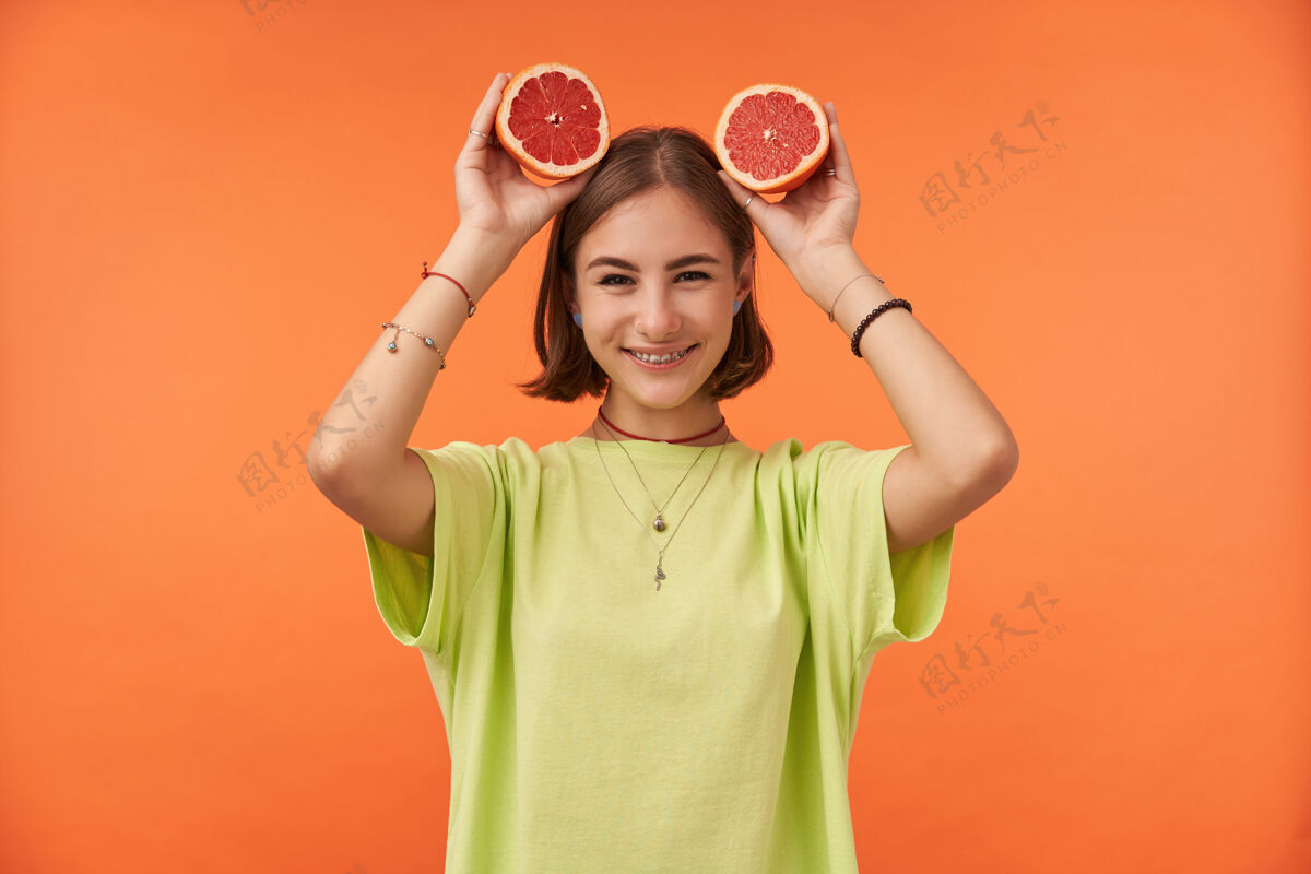 情感十几岁的女孩 快乐快乐 深色短发 头上戴着葡萄柚 穿着绿色t恤 戴着牙套和手镯多汁T恤葡萄柚