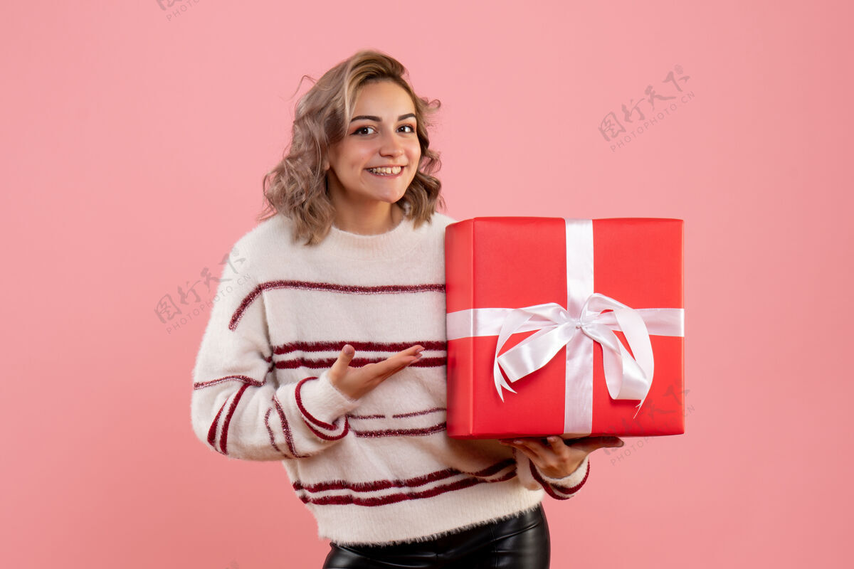 丝带手持圣诞礼物的年轻女性圣诞节礼物情感