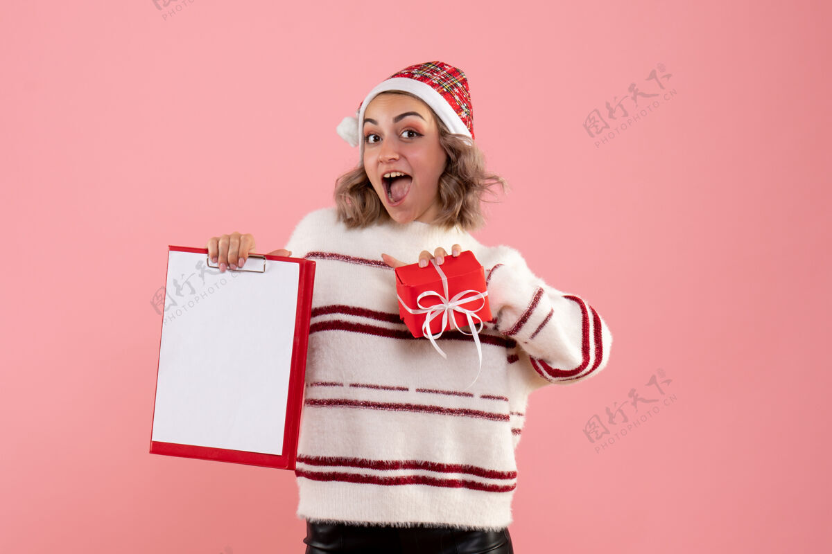 粉色年轻的女性拿着小圣诞礼物和粉红色的纸条拥抱情感女人