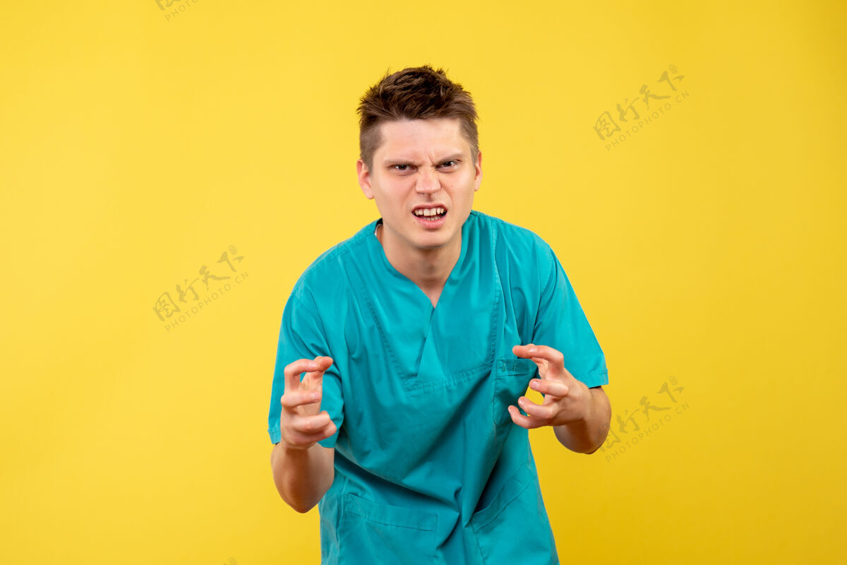 背景正面图黄色背景上穿着医疗服的年轻男医生医院药年轻的男医生