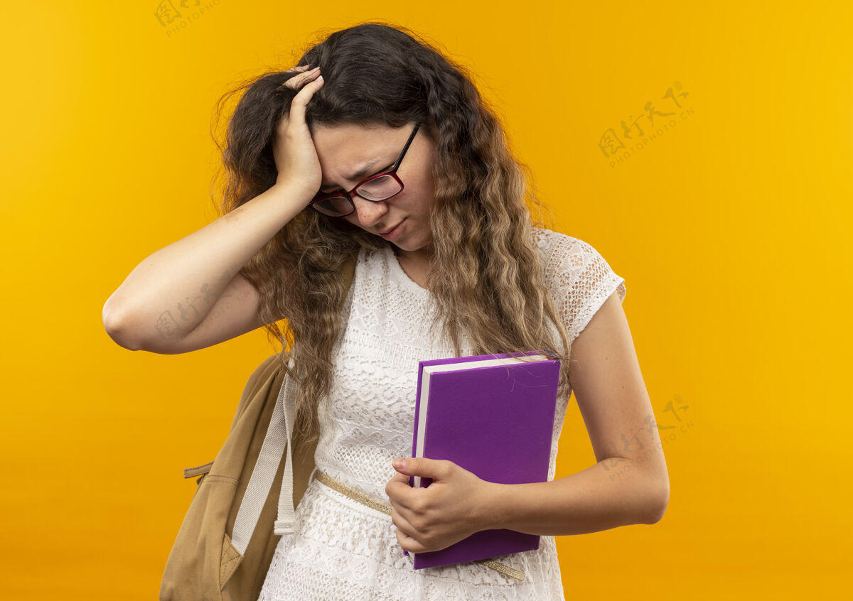 黄色戴着眼镜背着书包 手放在头上 眼睛发酸的年轻漂亮的女学生 低头看着隔离的黄色空间包女学生头