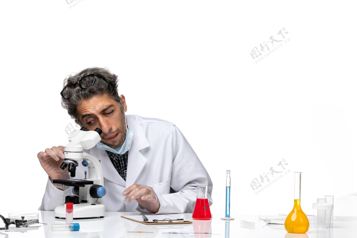 尝试前视图穿着白色医疗服的中年科学家正在尝试使用显微镜男性化学病毒