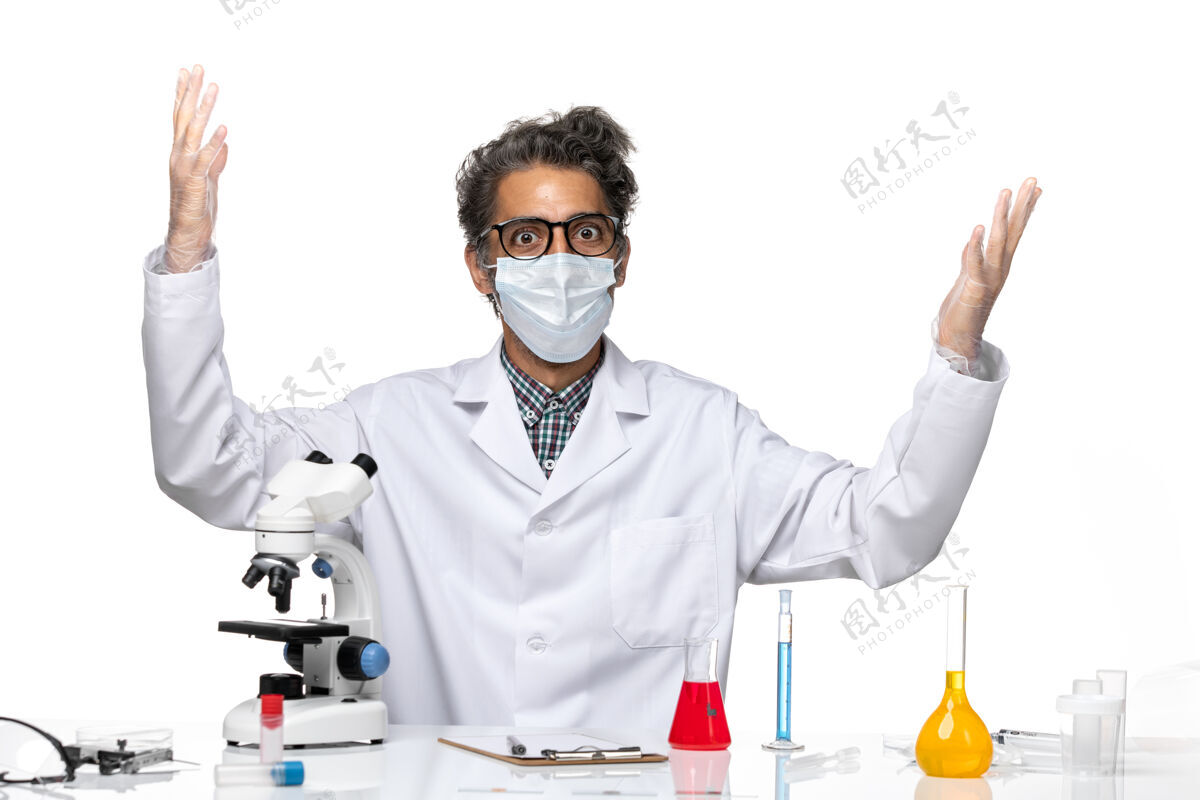 病毒前视图穿着白色医疗服的中年科学家围坐在桌子旁 拿着解决方案实验室坐桌子