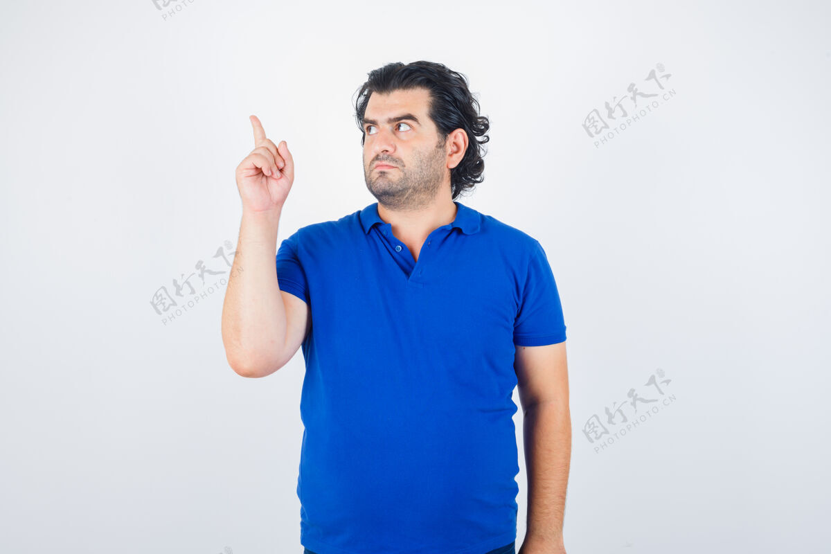 牛仔裤成熟的男人用食指指着左边 穿着蓝色t恤 牛仔裤 看起来很专注前视图男人力量前面