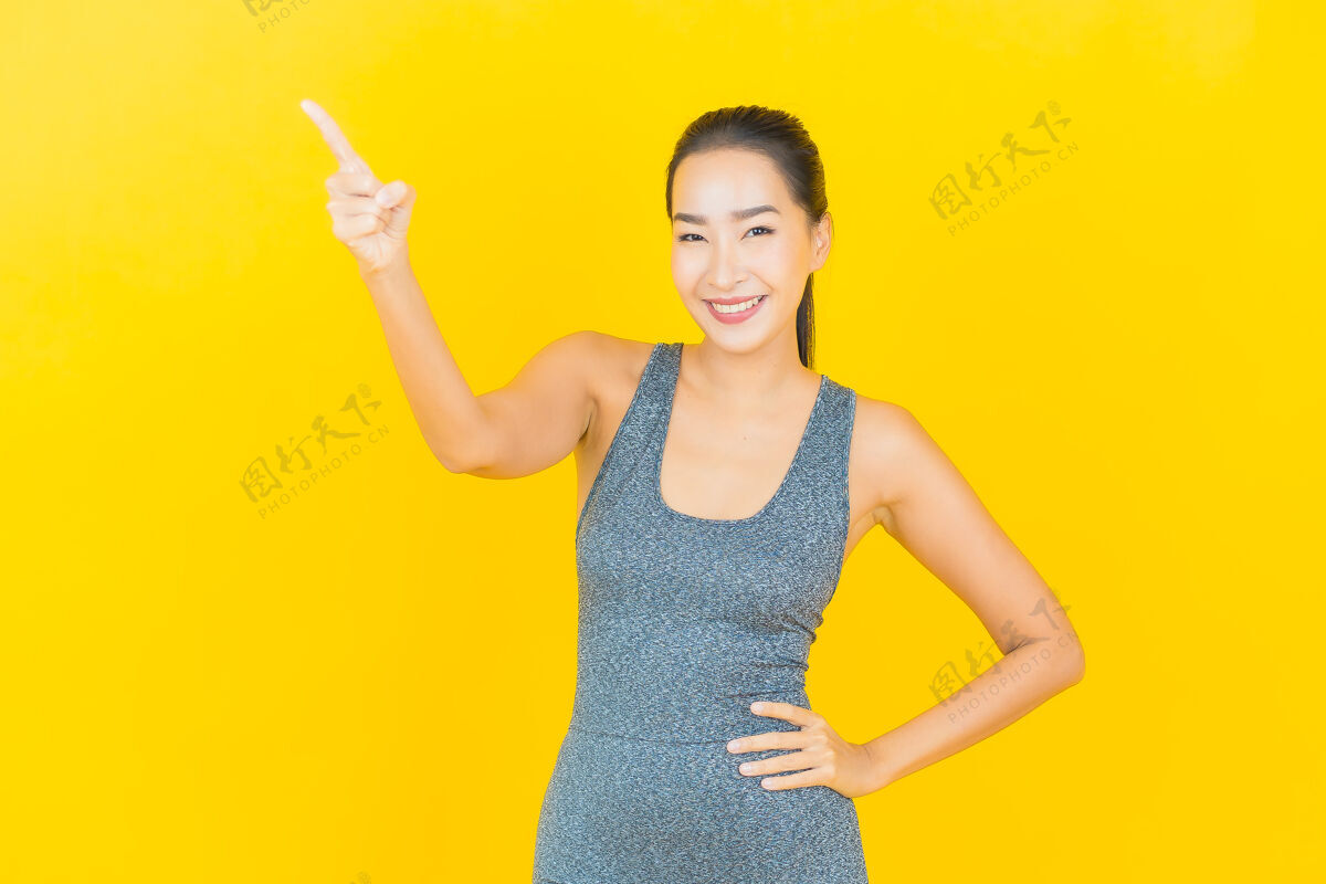 性感在黄色的墙上 描绘一位穿着运动服准备锻炼的美丽亚洲年轻女子放松运动装运动
