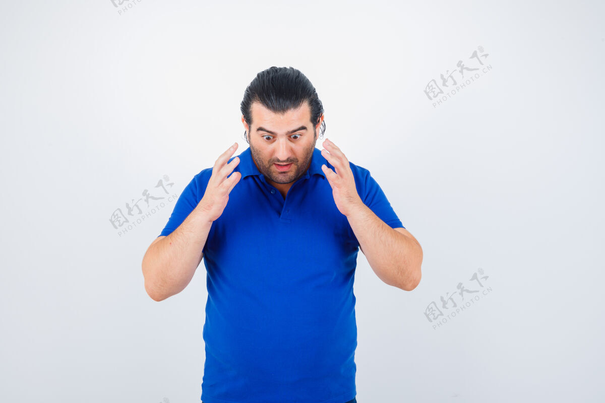 老年人身着蓝色t恤的中年男子举起双手放在胸前 面带困惑的表情兴趣提高思想