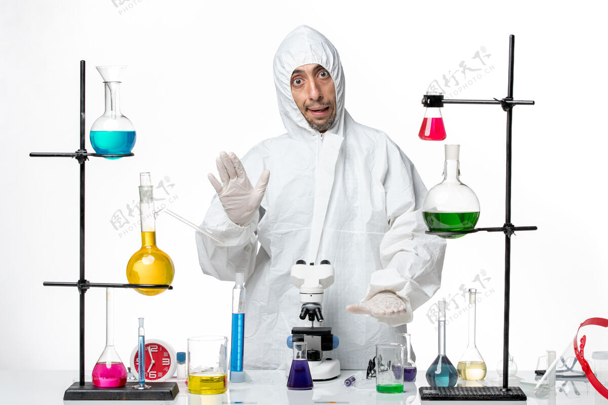 实验室正面图穿着特殊防护服的男科学家站在桌子周围 拿着解决方案科学支架周围