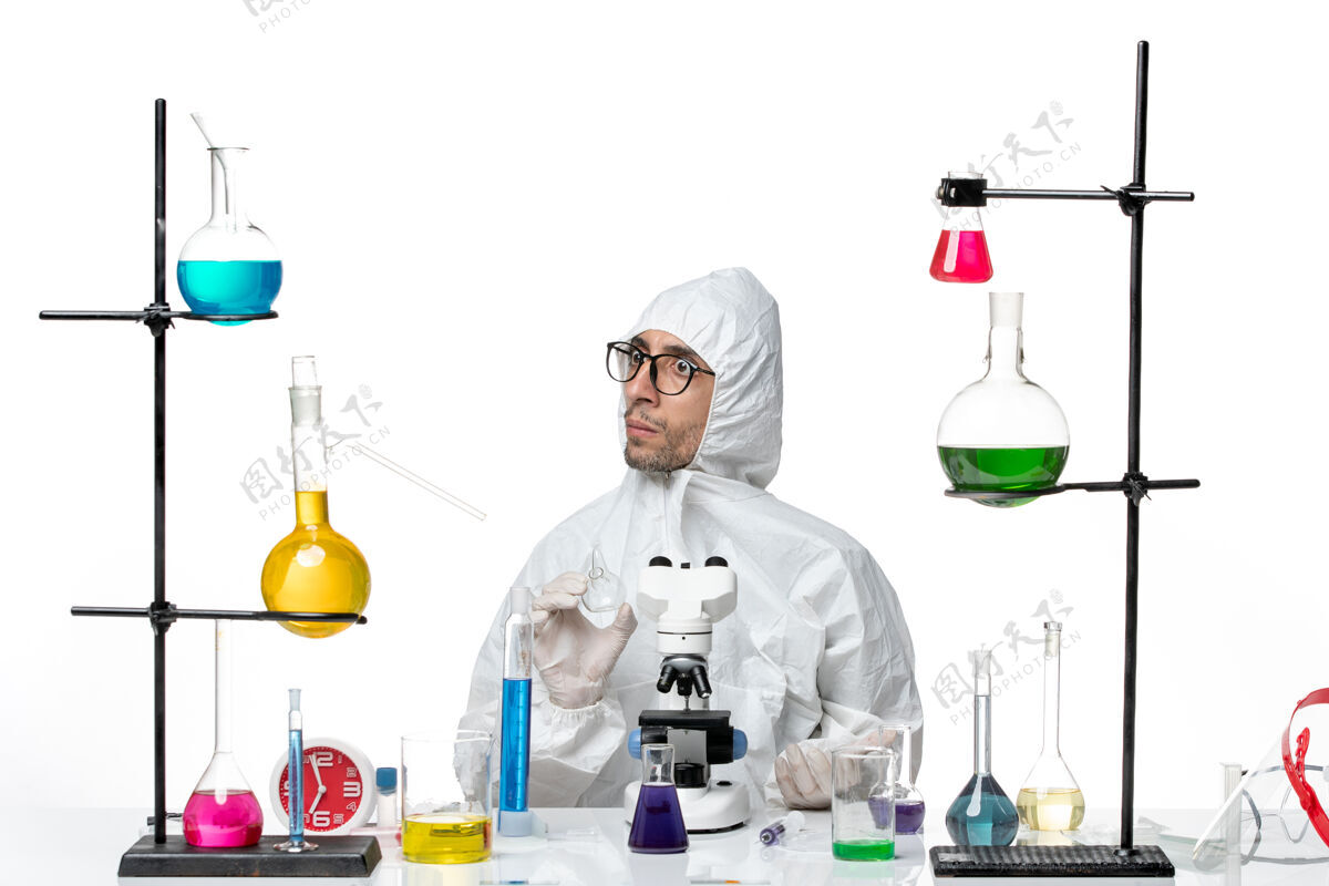 科学正面图穿着特殊防护服的男科学家坐在不同的解决方案医学科学玻璃
