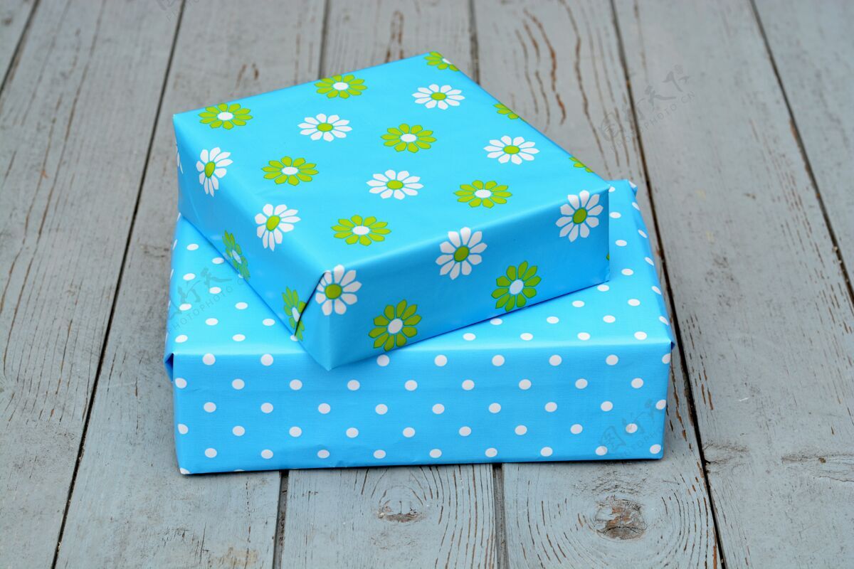 圣诞节特写镜头的两个礼品盒在蓝色包装堆叠在一个木制表面上的对方顶部礼物波尔卡地板