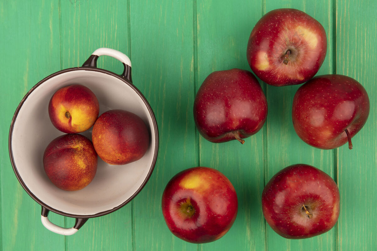 食品一个碗上的甜桃子的俯视图 红色的苹果被隔离在绿色的木墙上新鲜观点木材