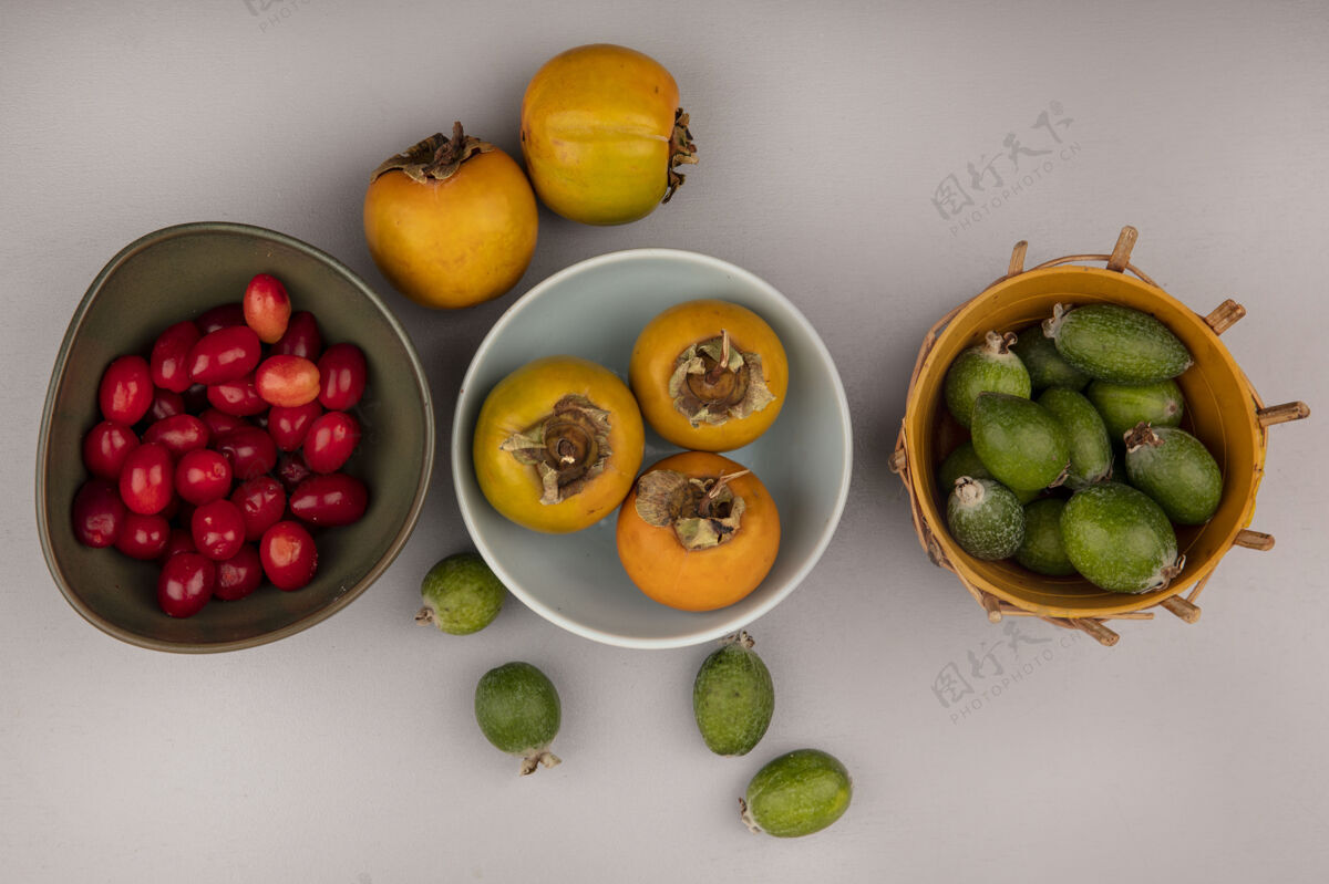午餐橘子柿子水果放在碗里的顶视图 桶上有飞珠 灰色墙壁上的碗上有山茱萸樱桃甜点食物水果