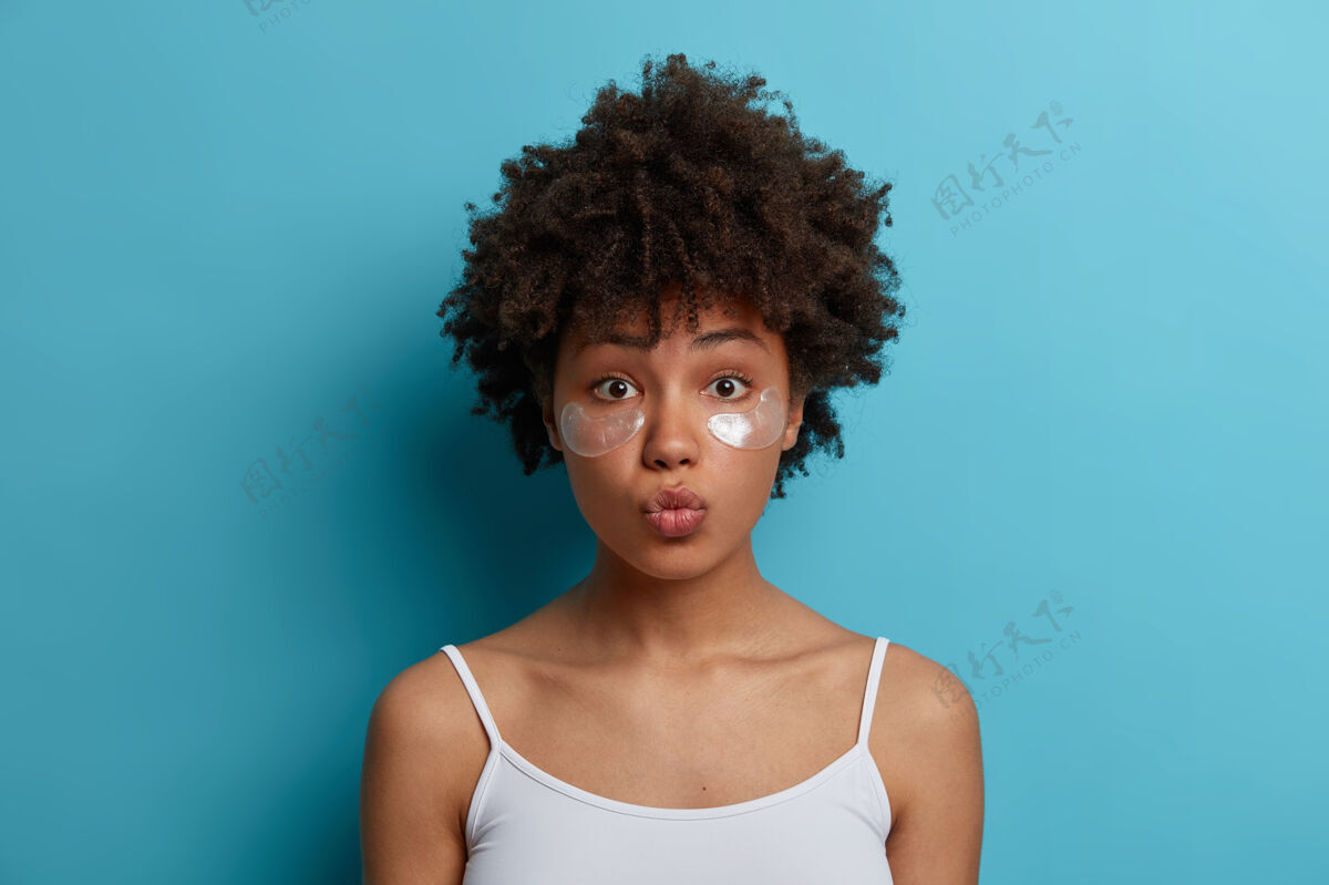 护肤年轻的黑皮肤非洲头发的女人在眼睛下面涂上水凝胶银片 减少浮肿 去除黑眼圈护肤理念过程健康女人
