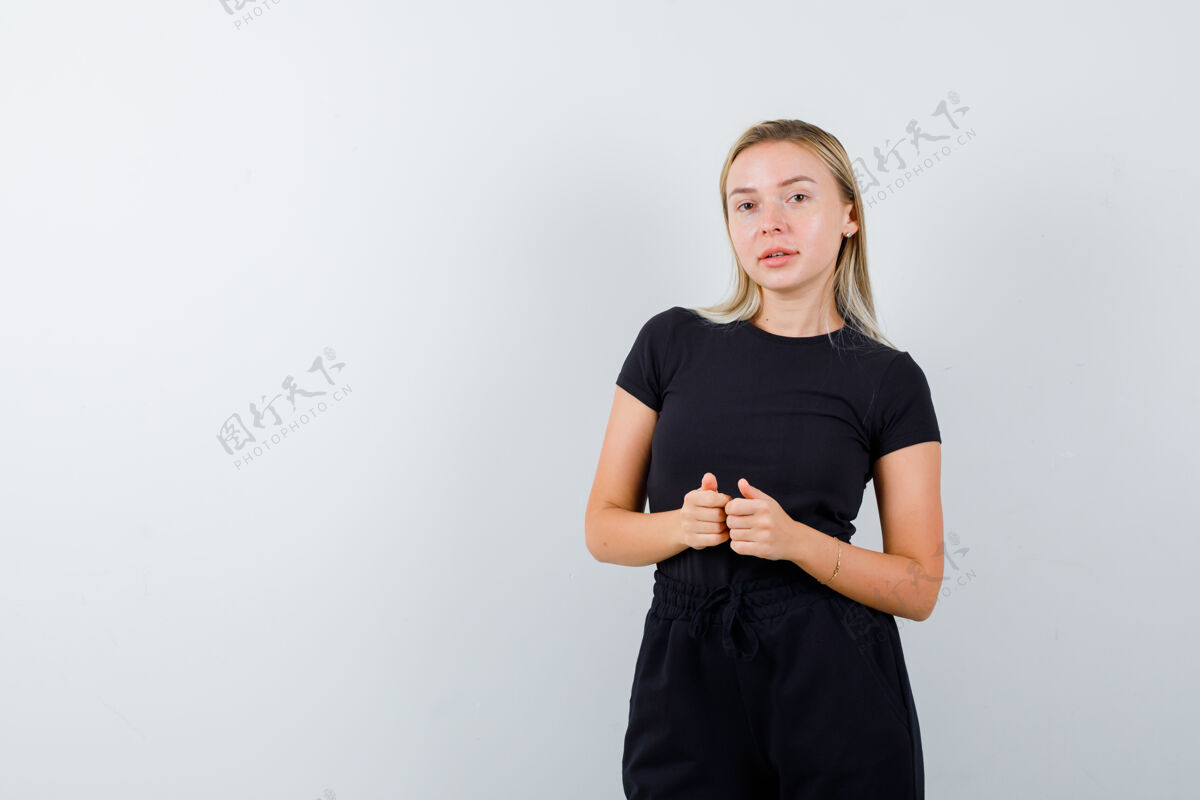 皮肤穿着t恤 裤子的年轻女士竖起大拇指 看上去很小心 正面视图面部护理惊喜