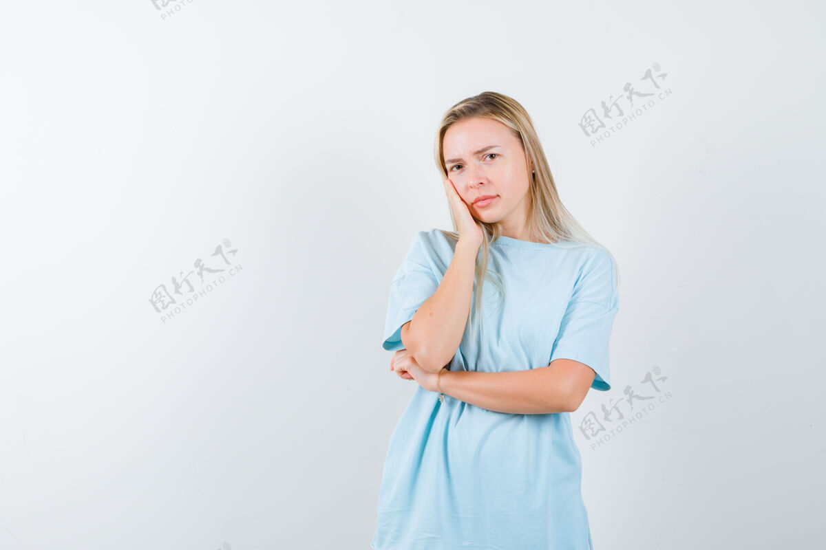 人年轻的女士枕着她的脸在她的手上 在t恤衫和期待体贴 前视图清洁人女人