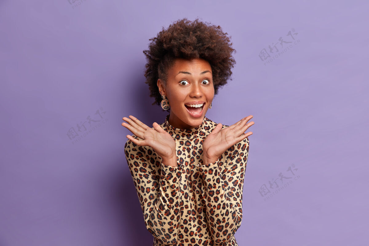 庆典快乐的黑皮肤女人 自然卷曲的头发 从喜悦中抬起手掌 笑容灿烂 听到好消息自然乐观发型