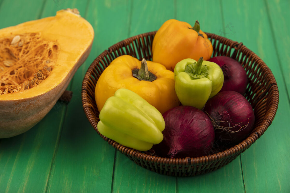 蔬菜顶视图新鲜的五颜六色的甜椒在一个桶与红洋葱南瓜隔离在绿色的木墙上木头餐烹饪