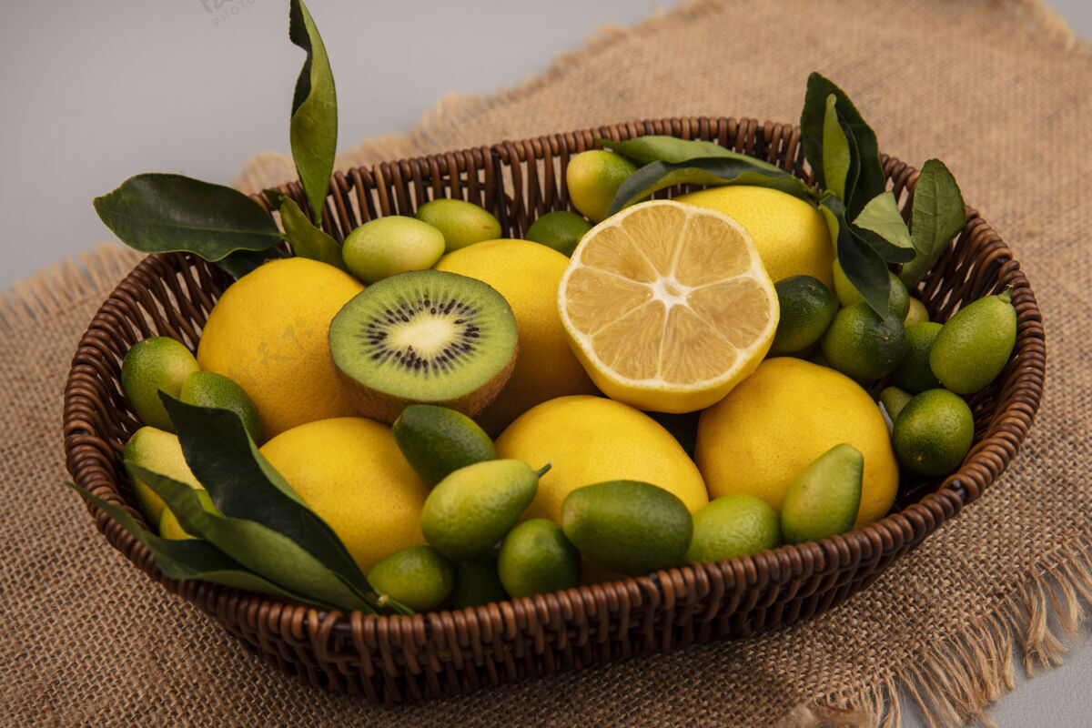 人顶视图健康水果 如猕猴桃金盏花和柠檬桶上的麻袋布上的灰色墙壁猕猴桃观点柠檬