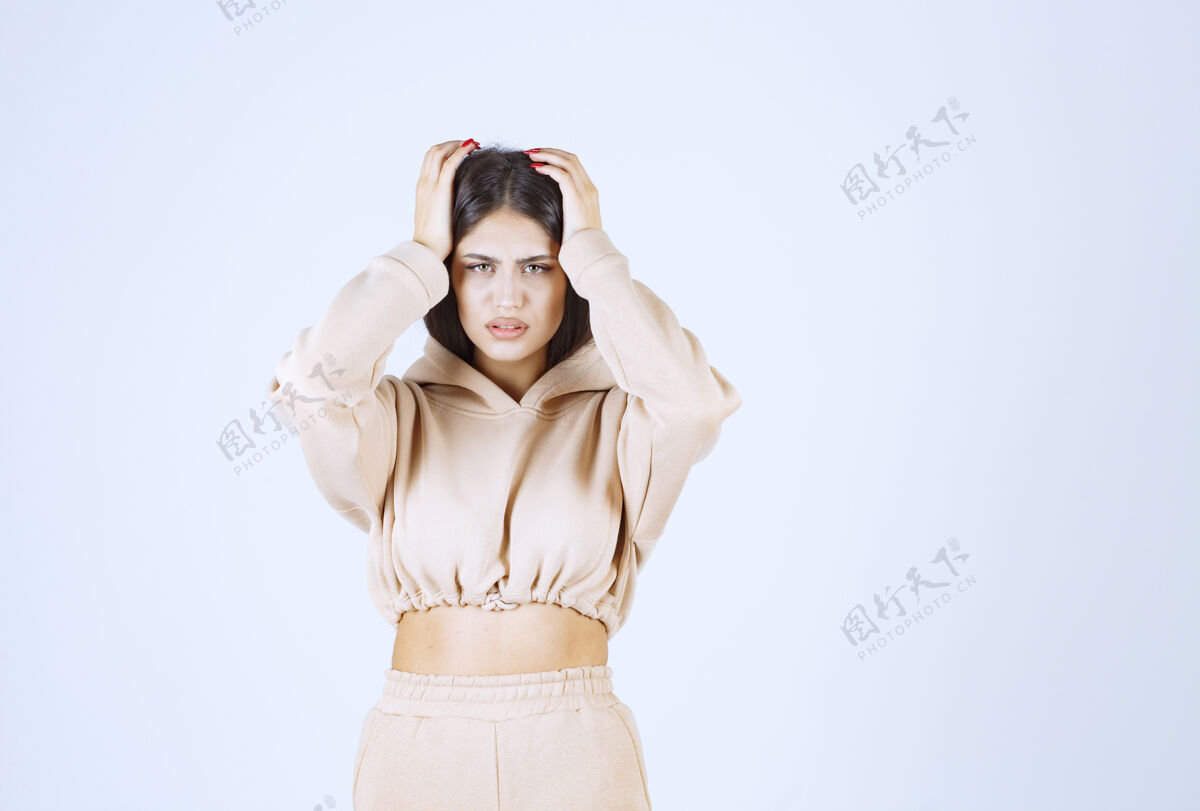 模特一个穿着粉色连帽衫的年轻女人因为头痛而抱着头痉挛疲惫女性