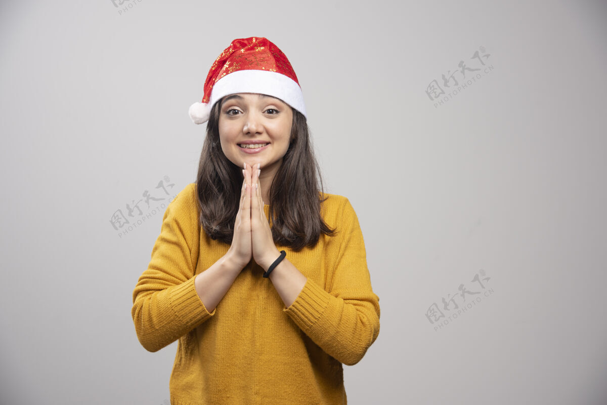 礼品盒戴着圣诞帽的年轻女子在灰色的墙上感激不尽圣诞节漂亮模型