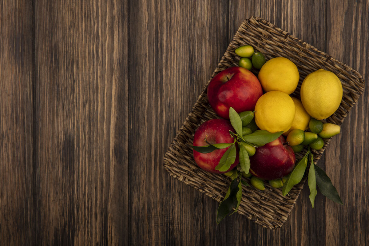 人顶视图的健康水果 如苹果 柠檬和金盏花在柳条托盘上的木制墙壁复制空间苹果健康膳食