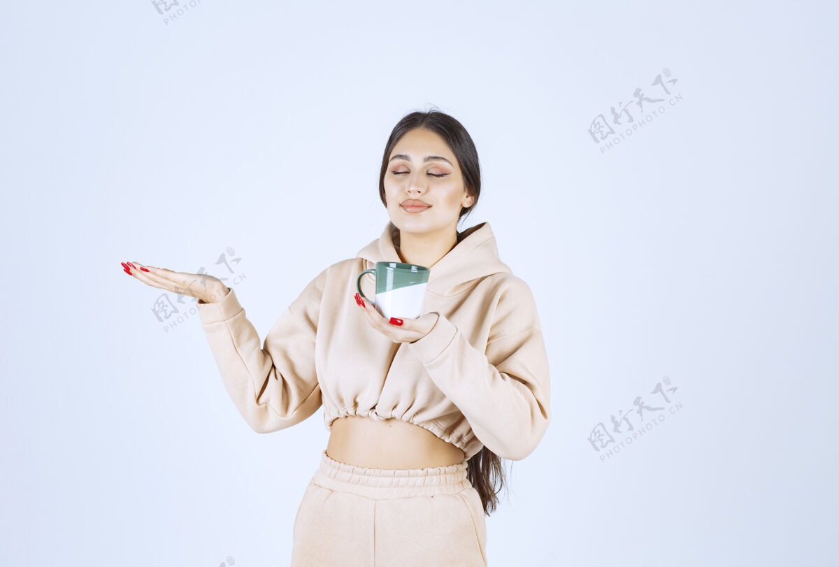 工人一个拿着绿色杯子的年轻女人指着左边的某个地方茶姿势年轻