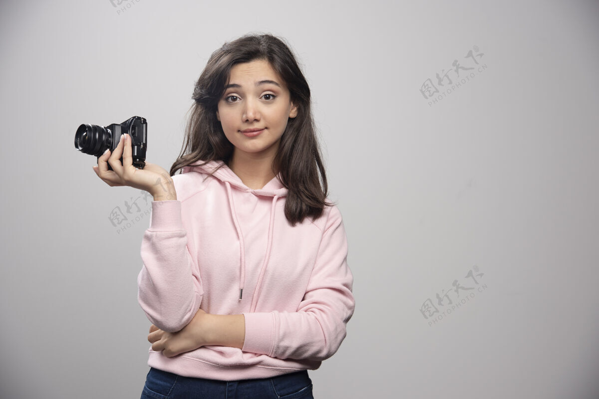 摄影师女摄影师在灰色的墙上和相机合影女孩肖像休闲