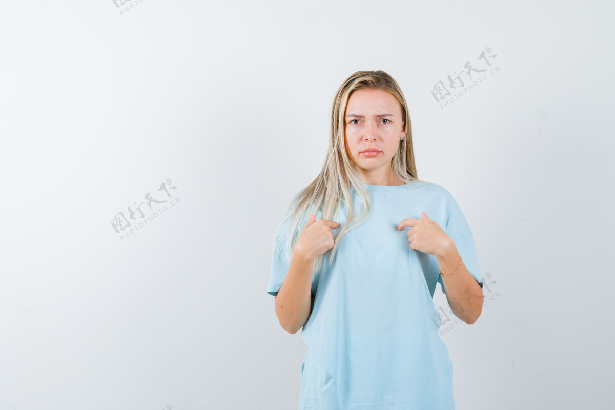 漂亮穿着蓝色t恤的金发女孩用食指指着自己 表情严肃正视图手指假期肖像