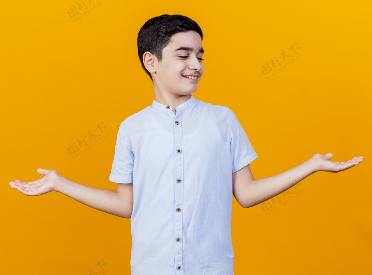男孩笑容满面的年轻白人男孩 两手空空地看着孤立在橙色背景下的他们年轻展示手