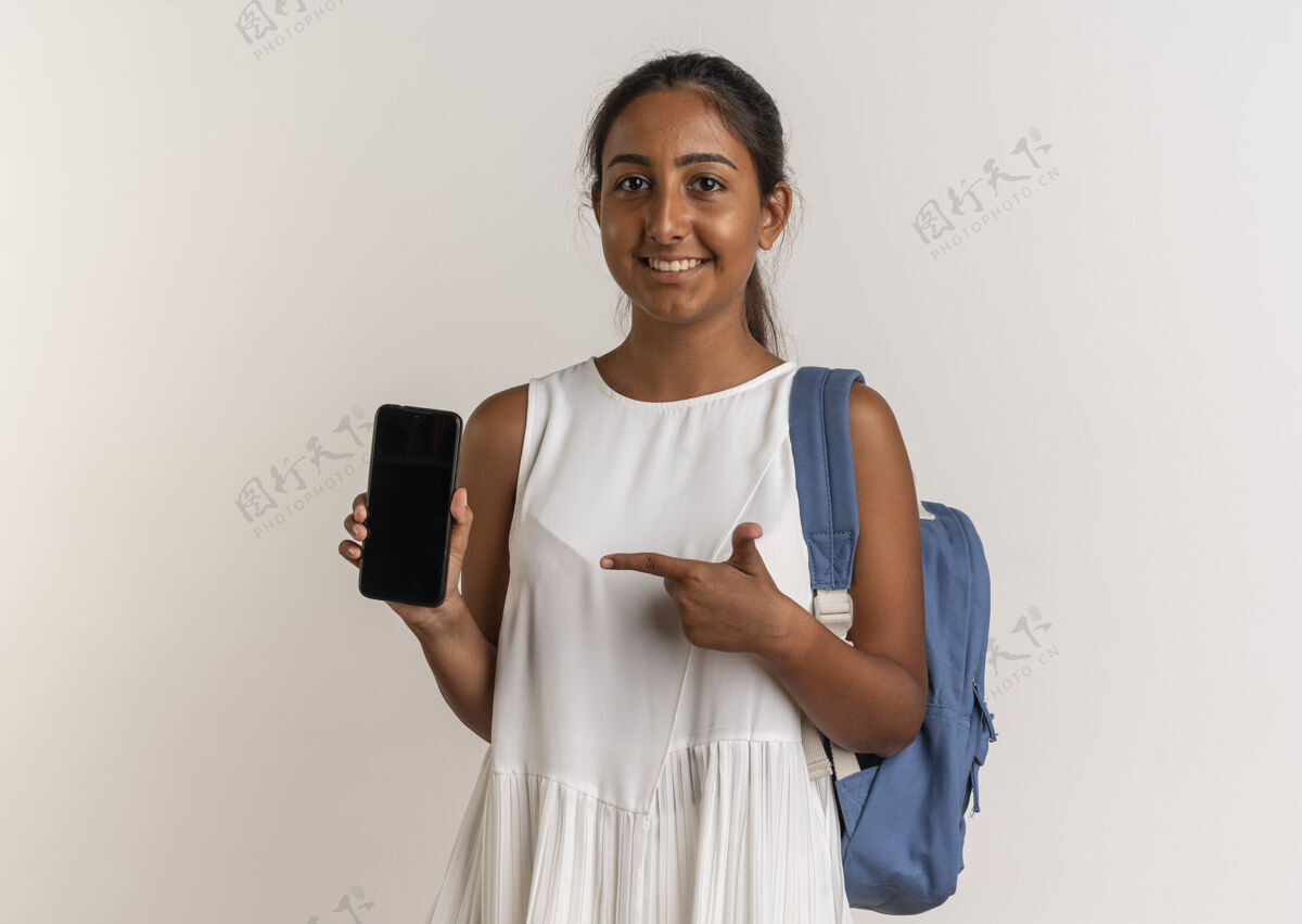 点带着微笑的年轻女学生背着书包 指着白色的手机女生背电话