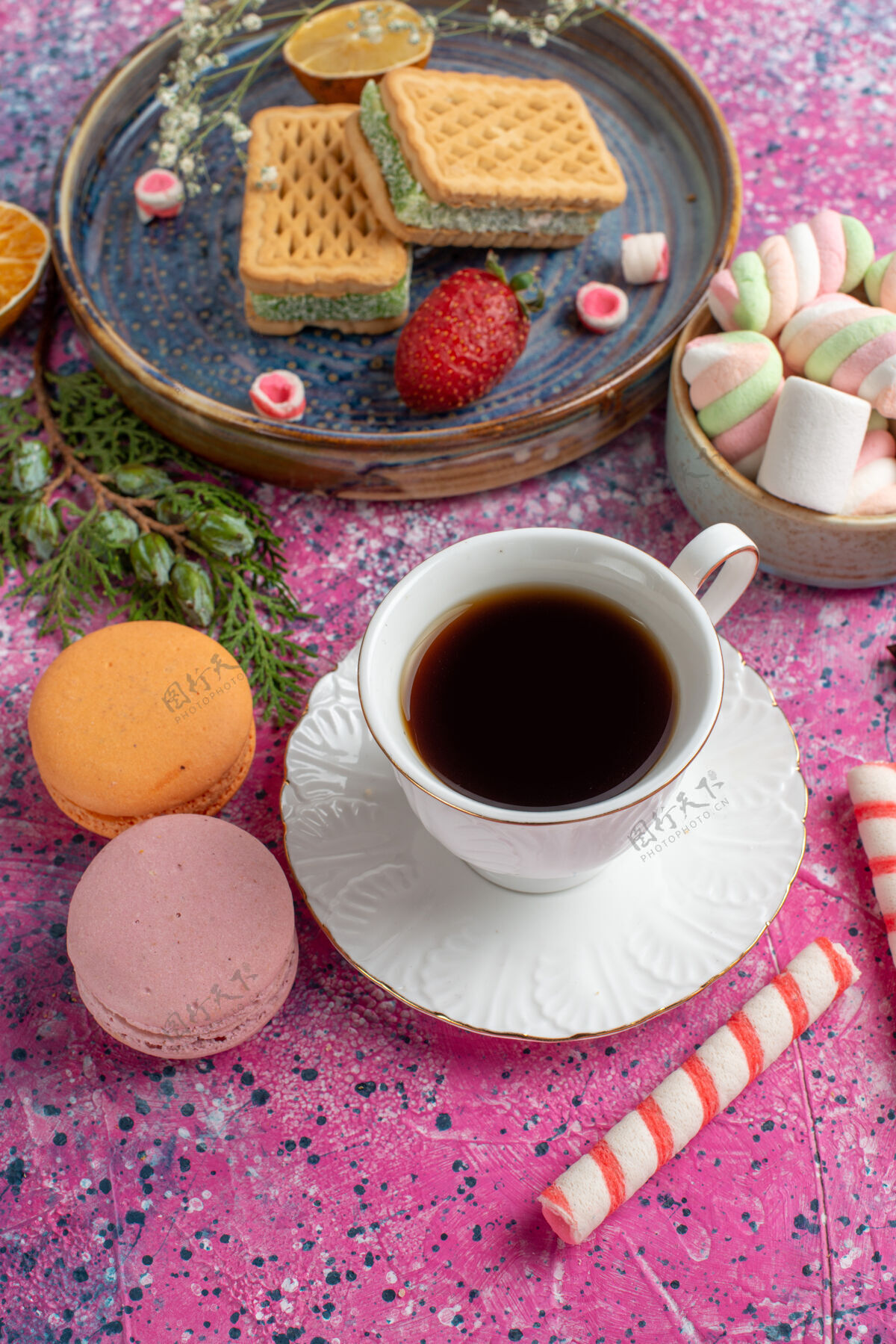 生的俯瞰美味的华夫饼 在粉红色的表面上放上一杯茶 麦卡龙和棉花糖提神棉花糖顶视图