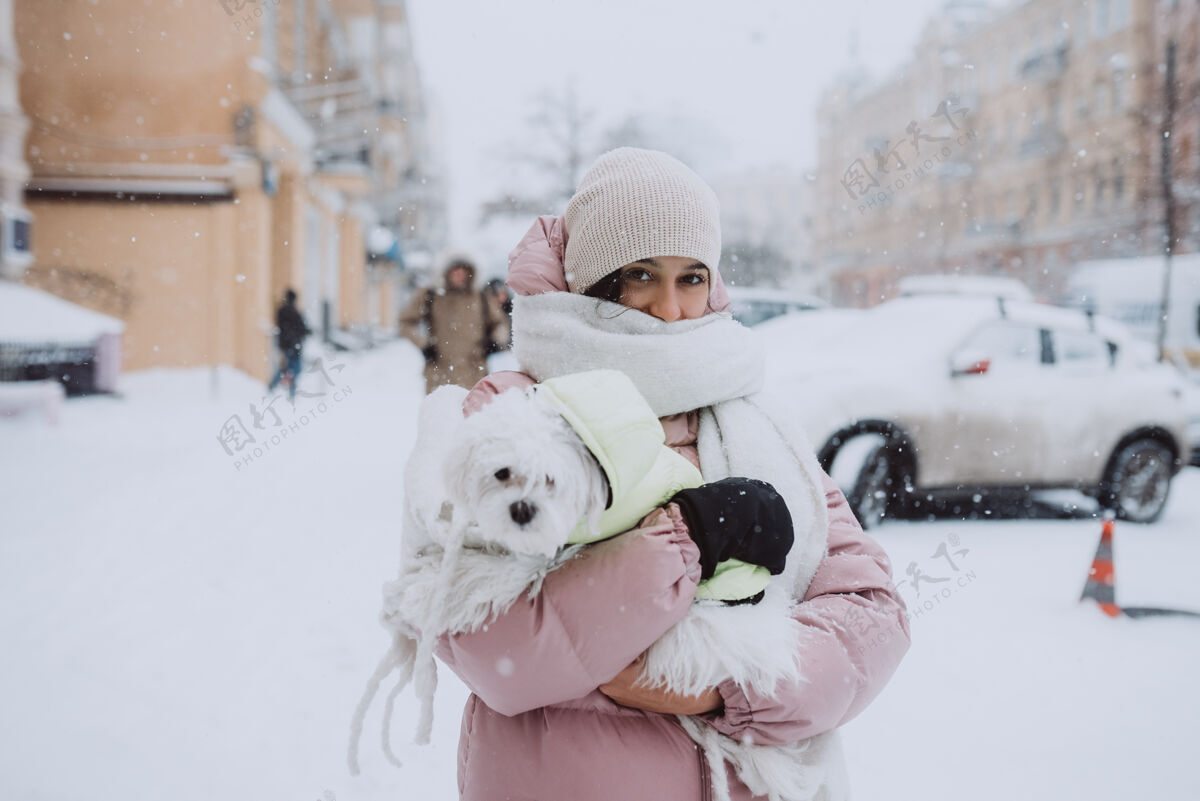 女人下雪时抱着狗的女孩女孩街道肖像