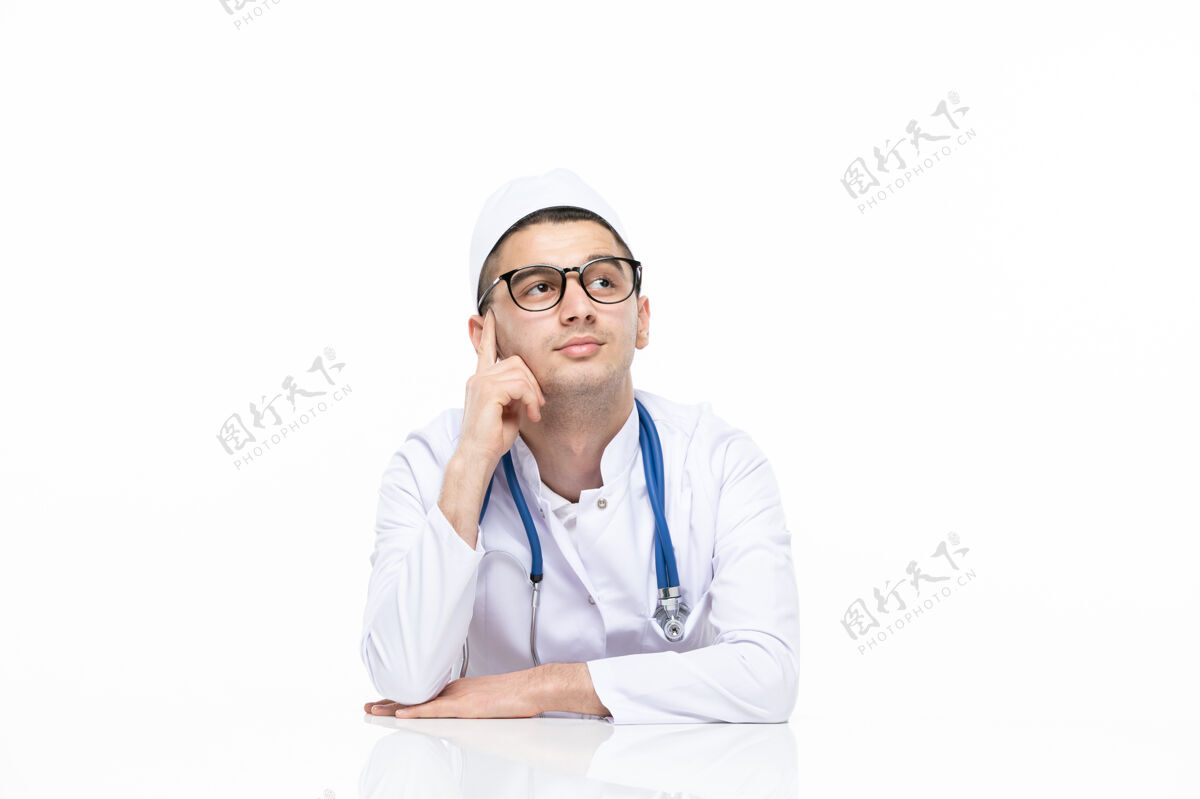 桌子正面图：年轻的医生穿着医疗服坐在桌子后面人医疗西装