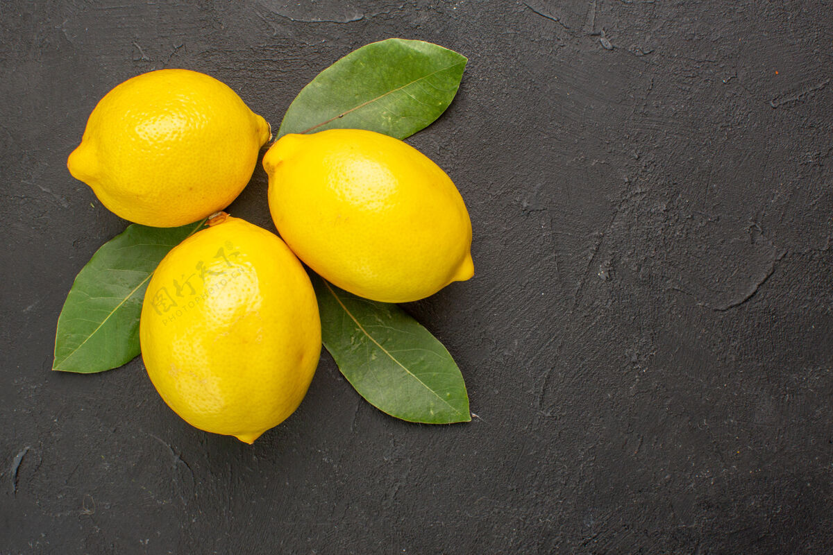 柑橘顶视图新鲜的酸柠檬和叶子放在深色的餐桌上 橙黄色的柑橘类水果黄色多汁叶子