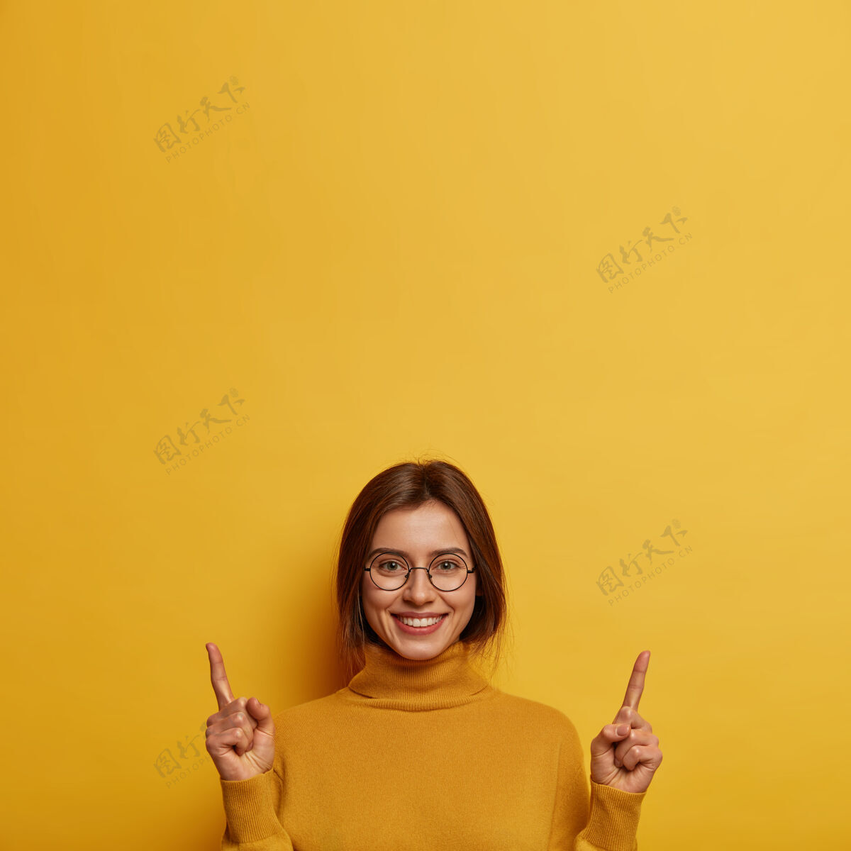 建议满意满意的年轻女子在上面推销产品 给人推荐 面带微笑地站在黄色的墙上看看那里欧洲女性把你的注意力转向横幅年轻广告人类